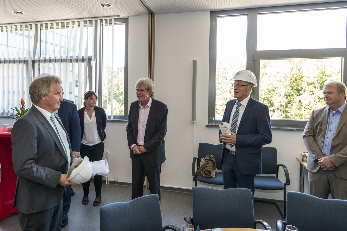 Kollege mit Bauhelm im Gespräch mit dem Team im Büro