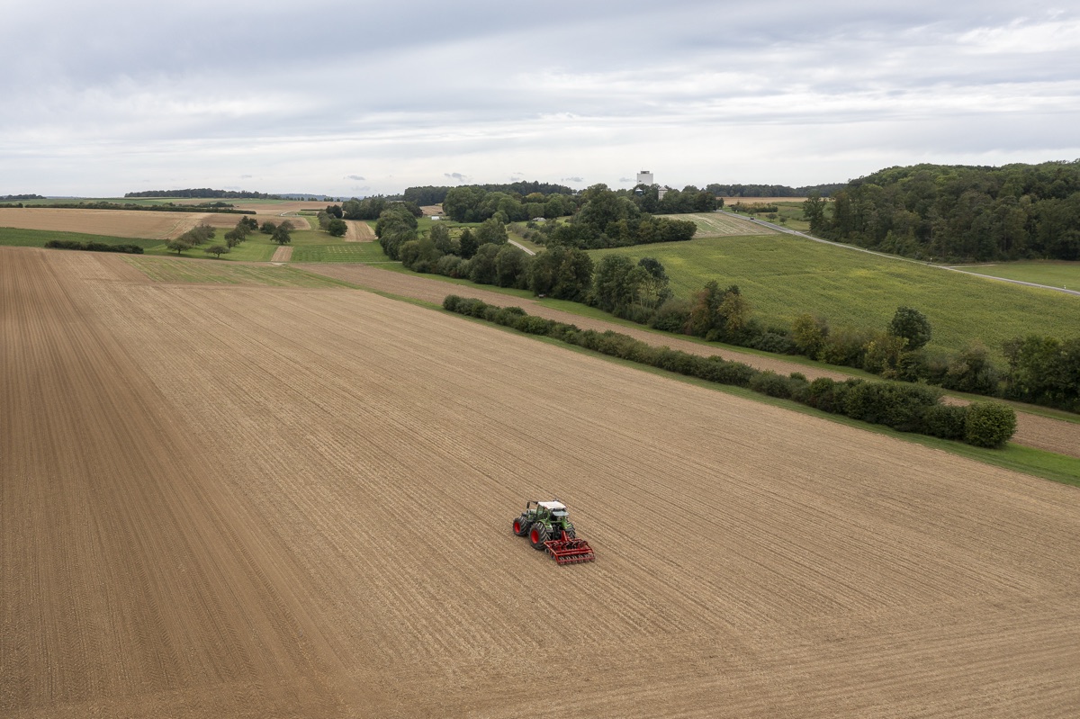 Traktor mit Strip-Till-Gerät bei der Feldbearbeitung, Luftaufnahme