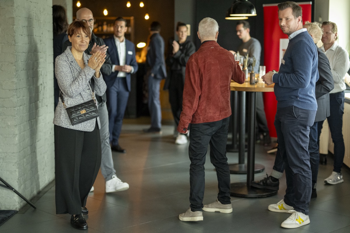 Business-Netzwerktreffen: Gäste im Gespräch, eine Frau applaudiert